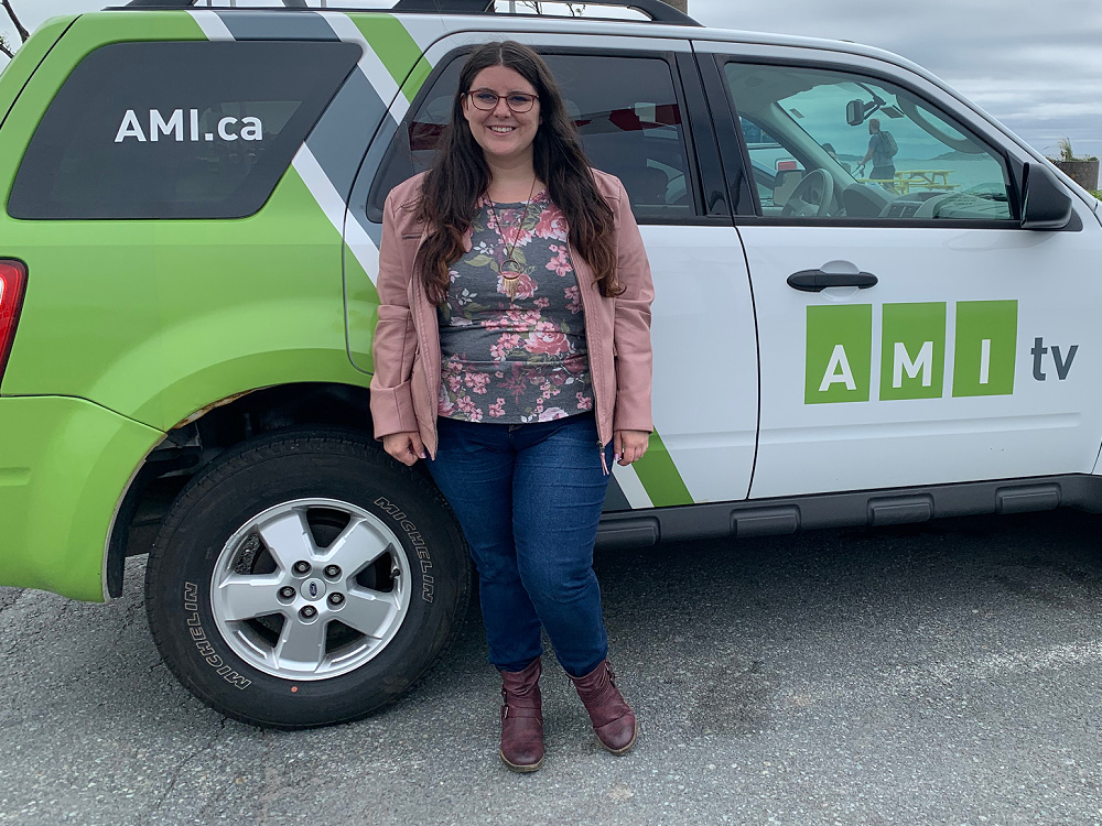 Jillian Gillis leans against an AMI production vehicle, smiling.